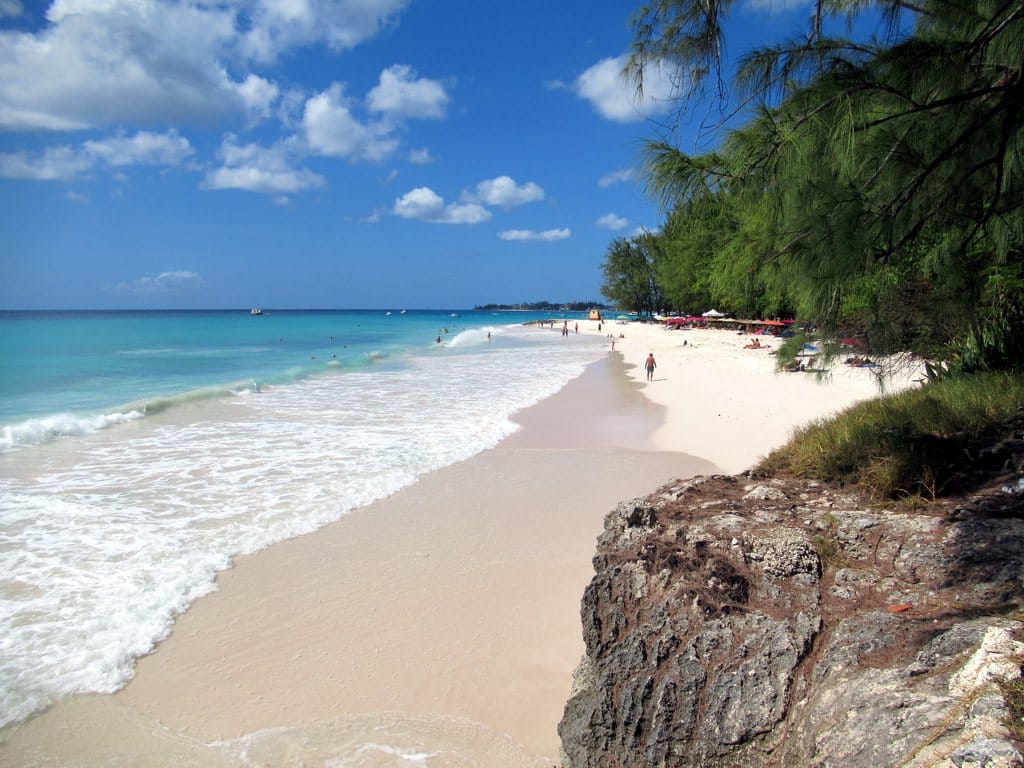 Barbados Caribbean beach with calm turquoise water, palm trees, white sand, direct flight planes arriving, luxury resort visible