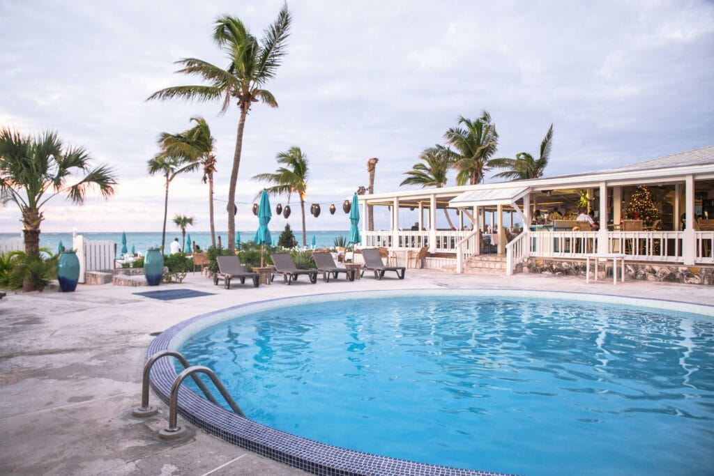 Family swimming in pool at luxury all-inclusive resort in Turks & Caicos with beach visible, premium family vacation