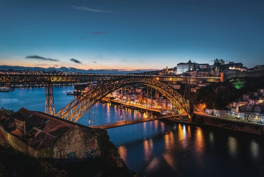 "Dom Luís Bridge in Porto, Portugal illuminated at dusk, representing Portugal's affordable and welcoming solo travel destination"