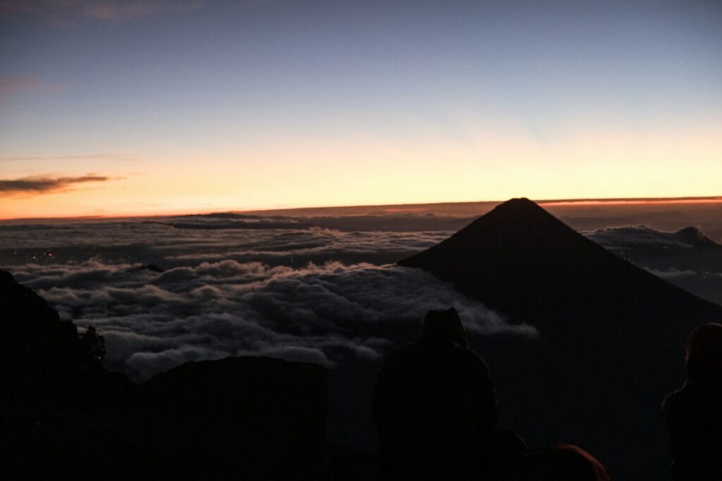 Acatenango volcano at sunrise with smoking Fuego volcano in background, highland landscape with indigenous villages visible below, dramatic mountain terrain