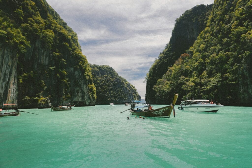 Traditional longtail boats on turquoise Thai water, representing Thailand's budget-friendly and accessible destination for solo female travelers"