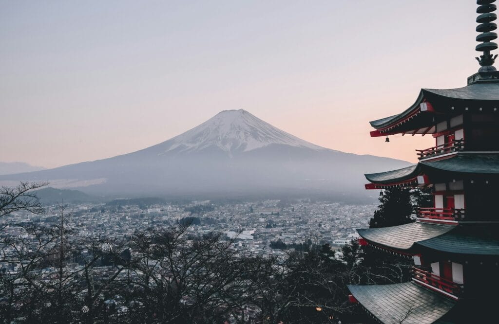 Traditional Japanese mountain village nestled in Yamagata prefecture with misty peaks in background, minimal crowds, traditional architecture visible