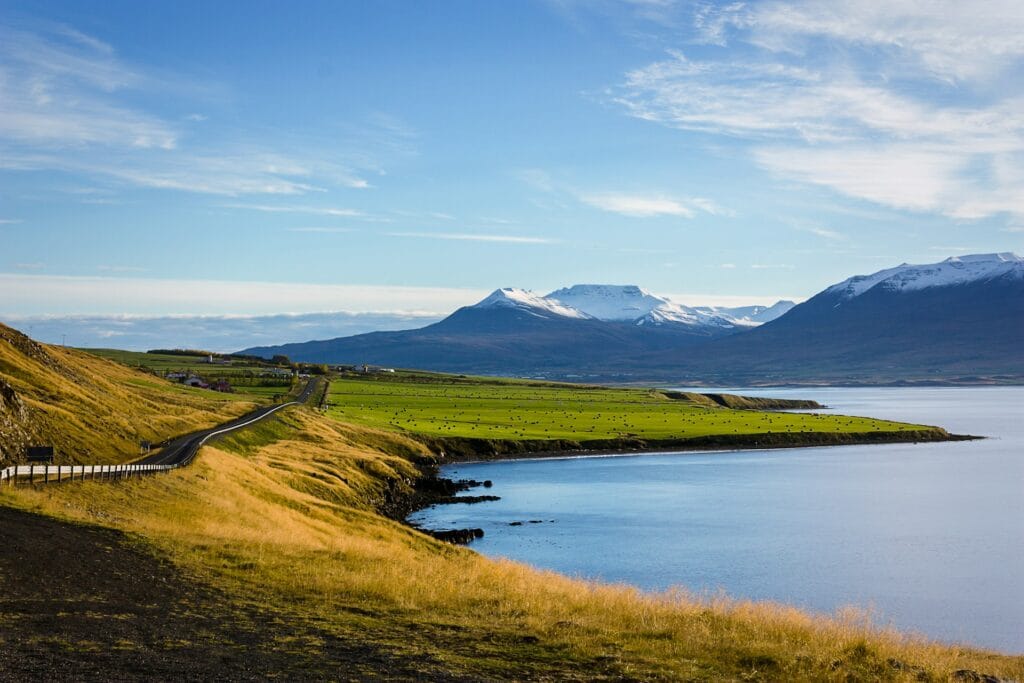 Iceland midnight sun over mountain landscape with golden light at 10pm, hiking trail visible, surreal summer daylight conditions
