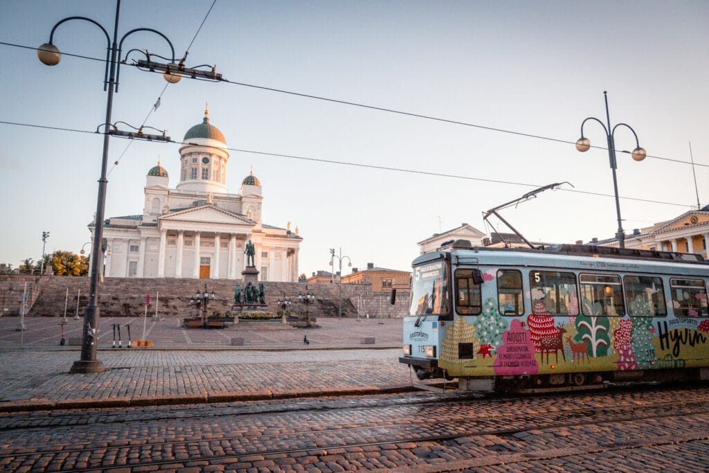 Yellow and white accessible tram on Helsinki street near white concrete building, modern public transport for wheelchair users