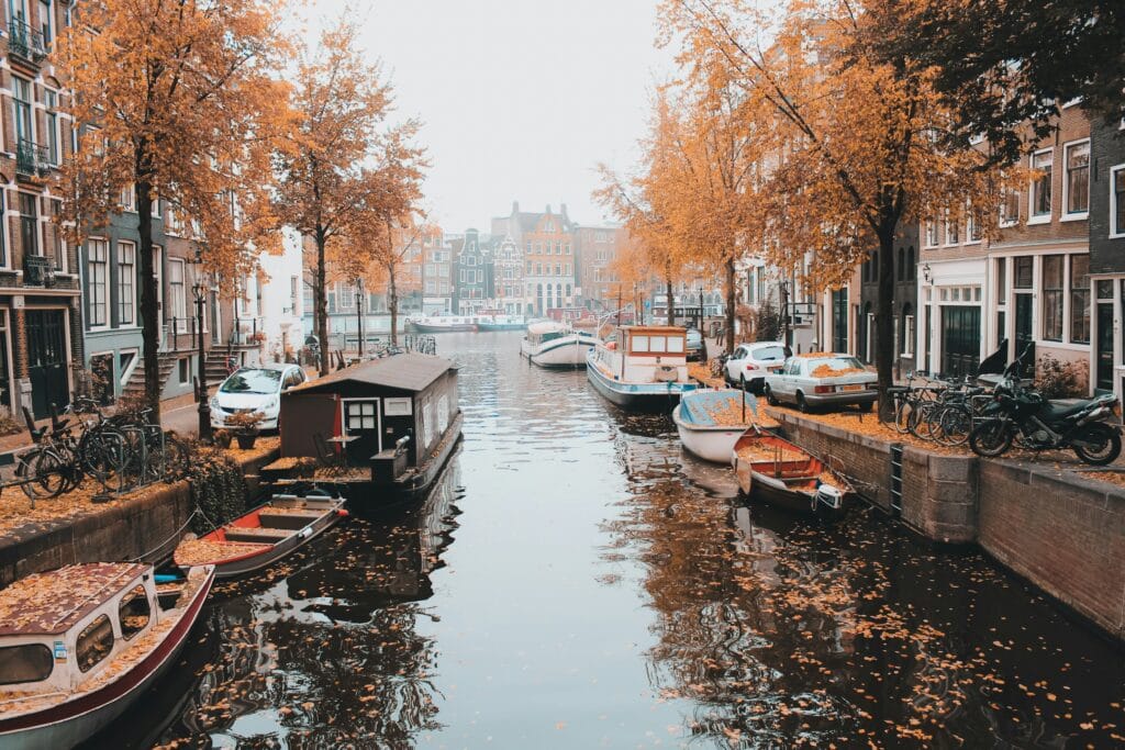 "Boat on Amsterdam canal with trees and bridges, representing the compact and easy-to-explore destination for first-time solo female travelers"