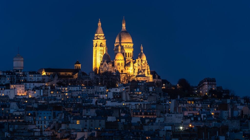 Montmartre basilica at night with illuminated dome, showing iconic landmark but illustrating steep hill terrain that makes wheelchair access extremely challenging