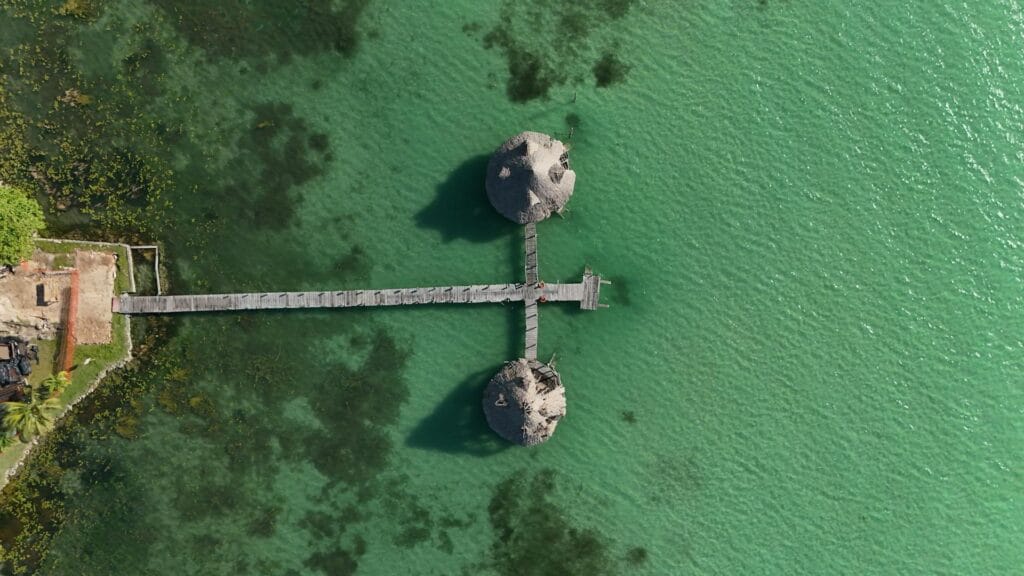 Bacalar Lagoon Mexico aerial view showing turquoise water and wooden pier, 7-colors lagoon budget beach destination