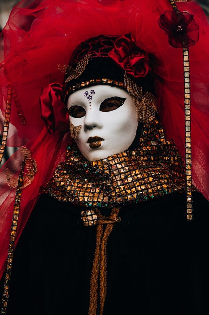 Person wearing ornate Venetian carnival mask with gold trim and elaborate design during Venice Carnival celebration
