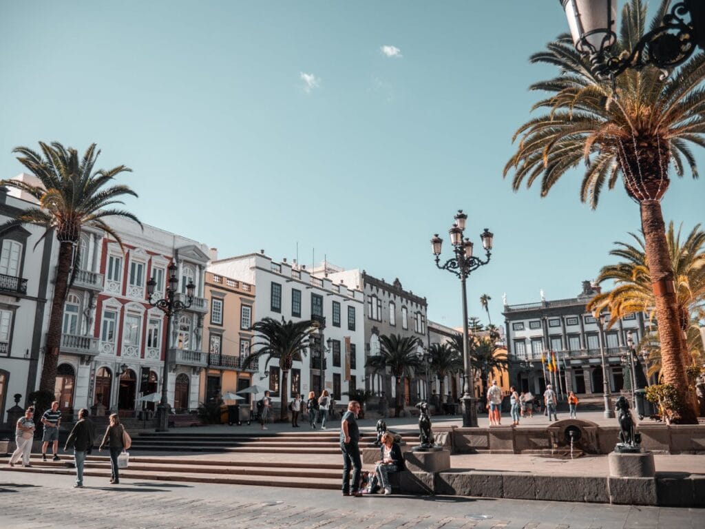Tenerife public plaza with palm trees, traditional Spanish colonial architecture, and people enjoying outdoor activities in warm weather
