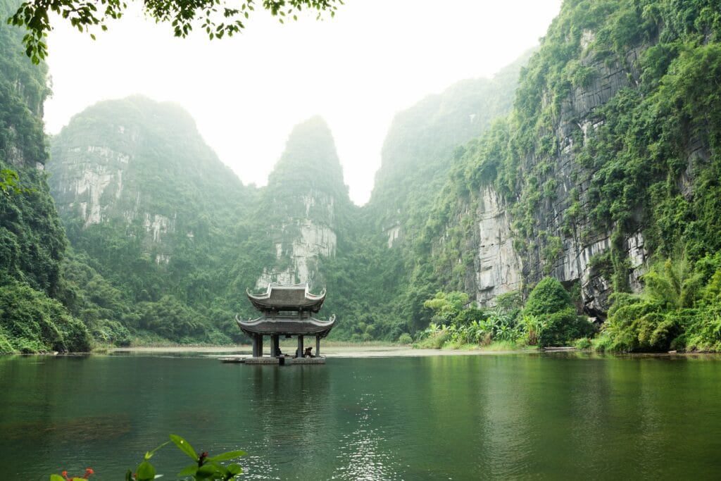 "Ancient pagoda surrounded by water and limestone mountains in Vietnam, representing Vietnam's empowering and ultra-budget solo travel destination"