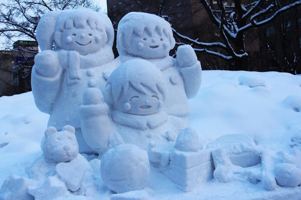 Enormous snow sculpture at Sapporo Snow Festival showing intricate carved details, with festival crowds and nighttime illumination visible