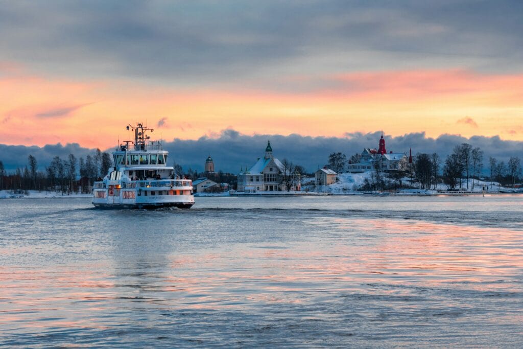 Helsinki ferry departing harbor with houses in background, fully accessible ferry service to Suomenlinna fortress