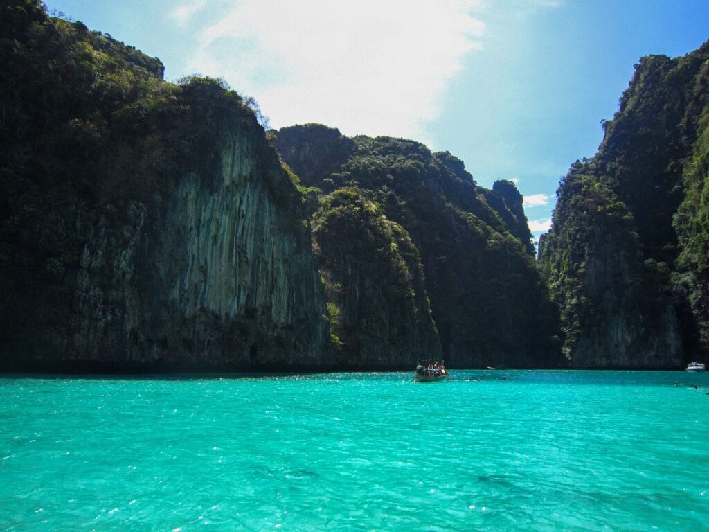 Phuket beach scene with turquoise water, palm trees, colorful beach umbrellas, and white sand showing peak season tropical beauty