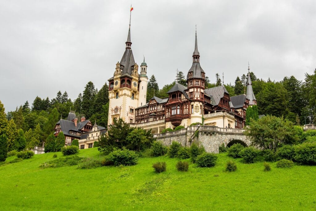 Mountain valley in Transylvania with medieval fortified church, green rolling hills, traditional village architecture, misty peaks in background