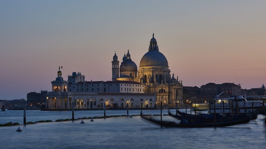 "Venice sunset with gondola on canal and historic architecture, representing Italy's romantic and walkable solo travel destination"