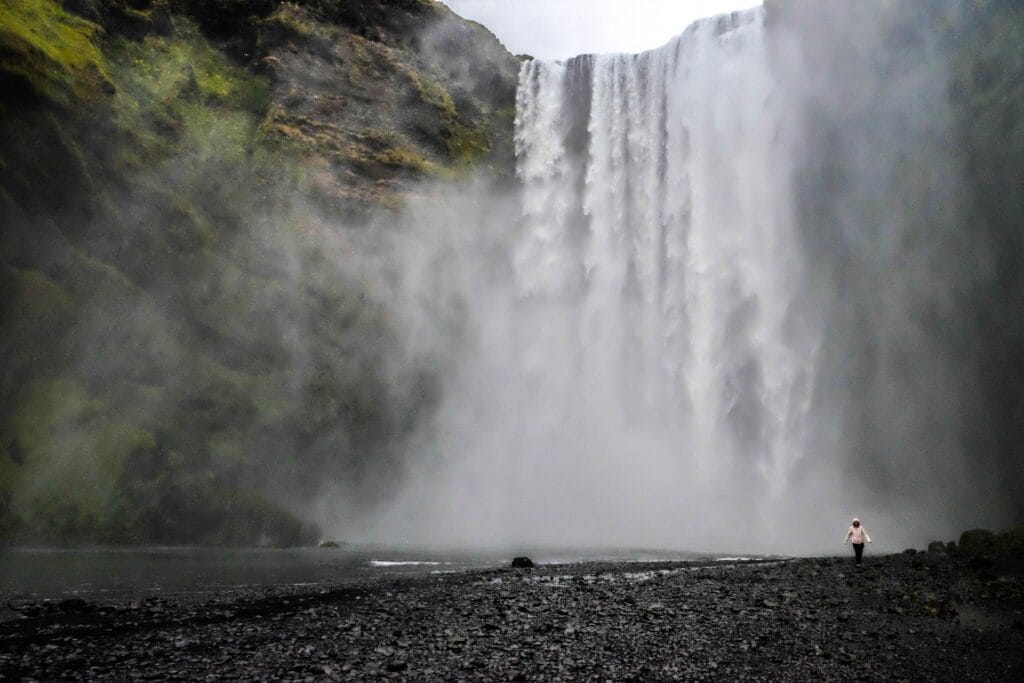 "Icelandic waterfall landscape with lush green moss and flowing water, perfect for solo female travelers"