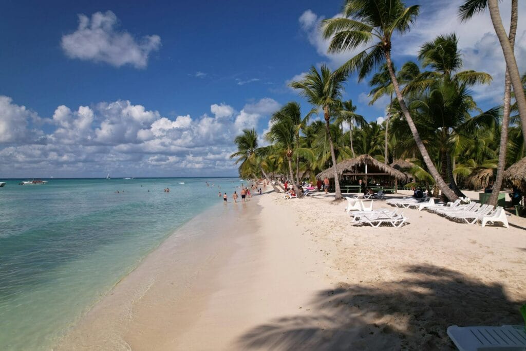 Tourists relaxing on a palm-fringed white sand beach in Punta Cana, Dominican Republic.