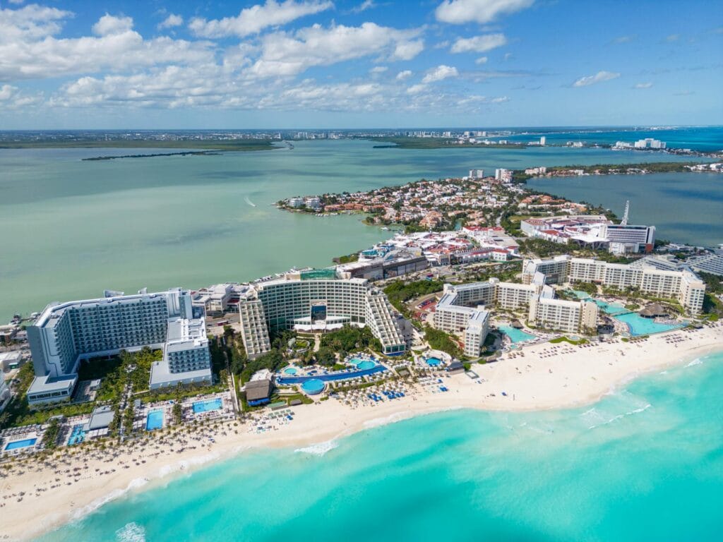 Aerial view of luxury beach resorts and crystal clear turquoise water in Cancun, Mexico, during the peak Spring Break 2026 season.