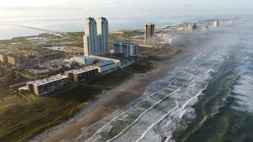 Foggy aerial view of the South Padre Island coastline and beachfront hotels along the Texas coast.
