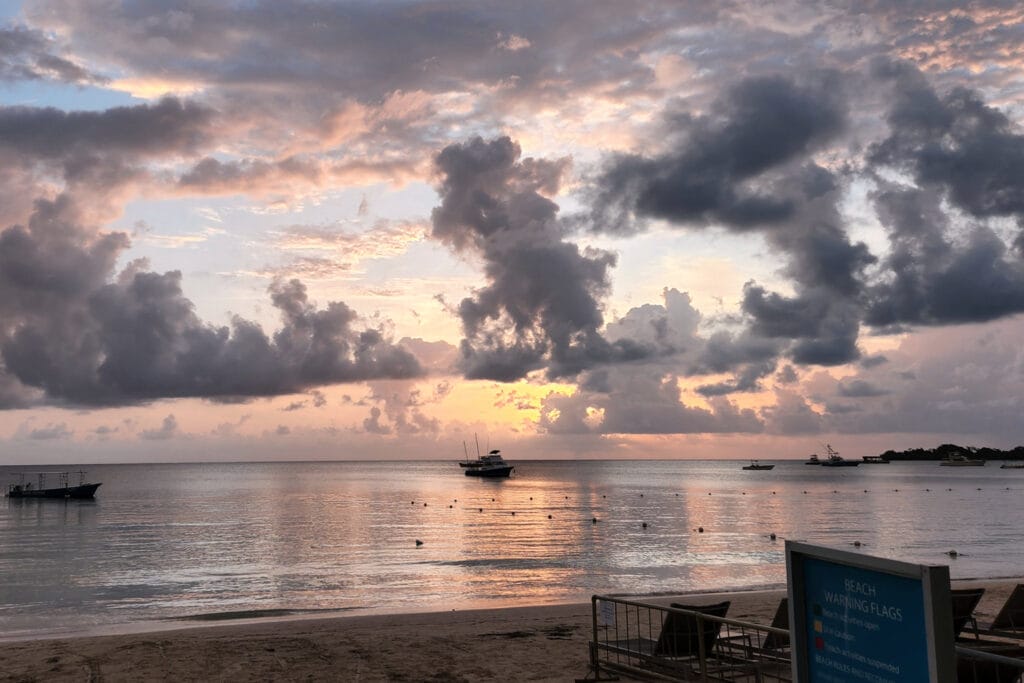 Sunset over the calm Caribbean Sea at Seven Mile Beach in Negril, Jamaica, with boats