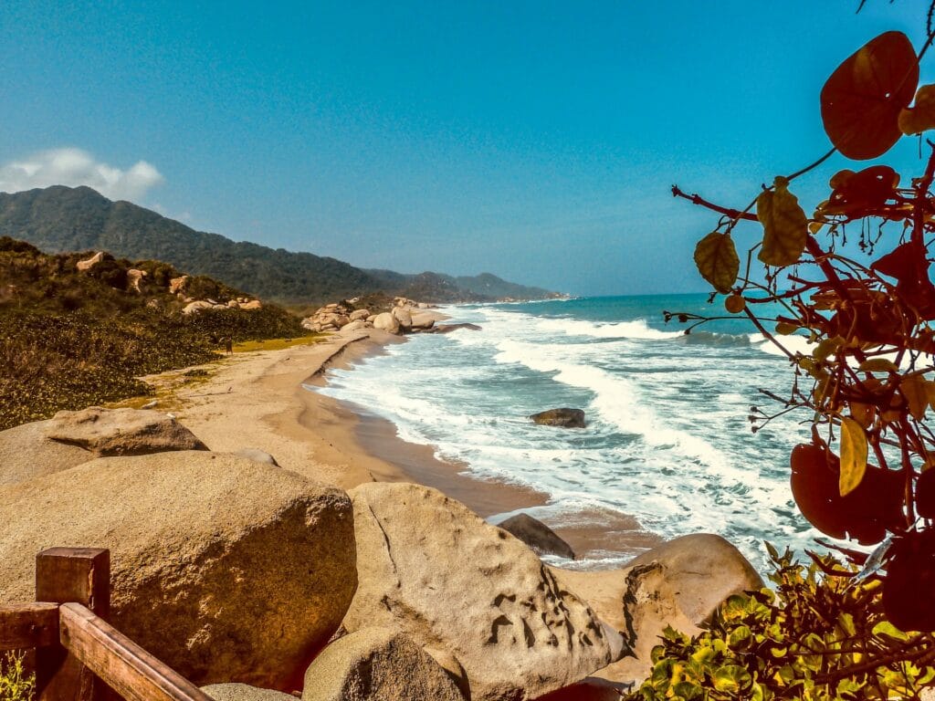 Dramatic brown rock formations and cliffs meeting the clear blue Caribbean Sea in Tayrona National Park