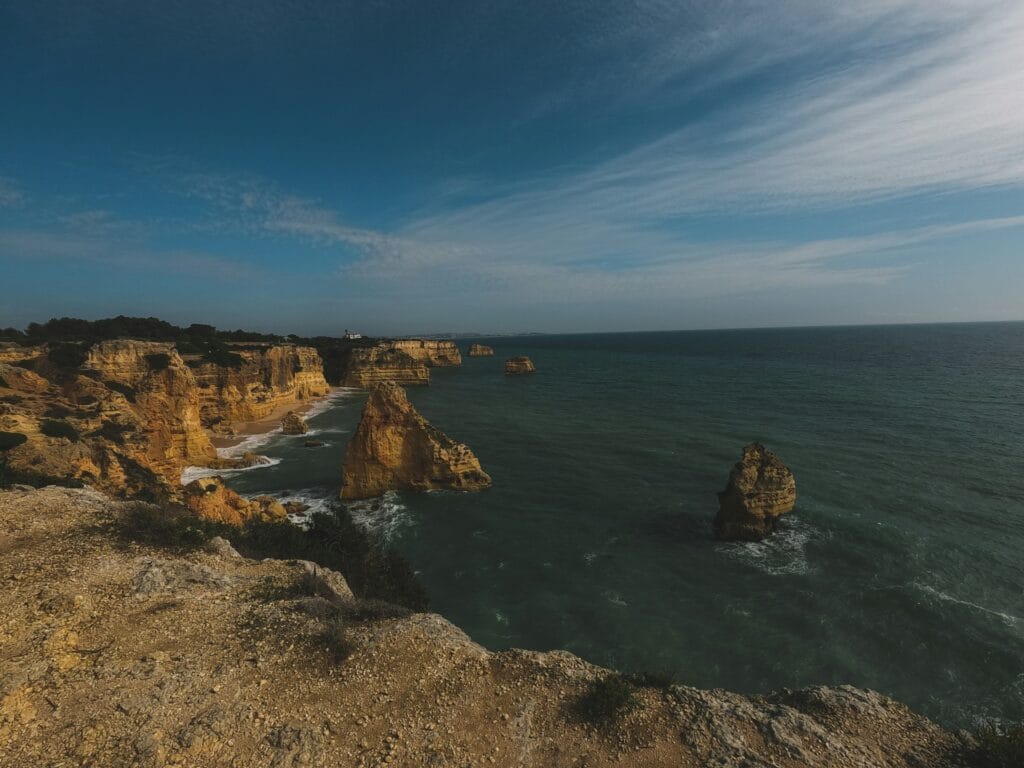 High-angle view of the ocean meeting the golden rocky cliffs of the Algarve coastline in Portugal
