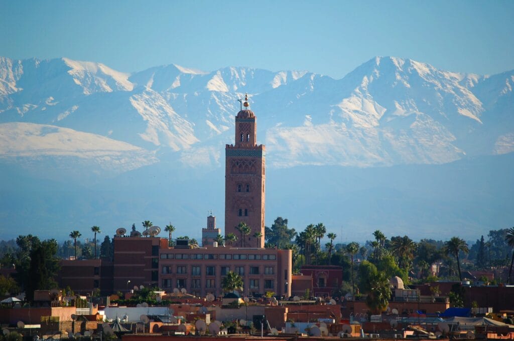 A traditional brown clay fortress or medina building at the foot of a rugged mountain in Morocco.
