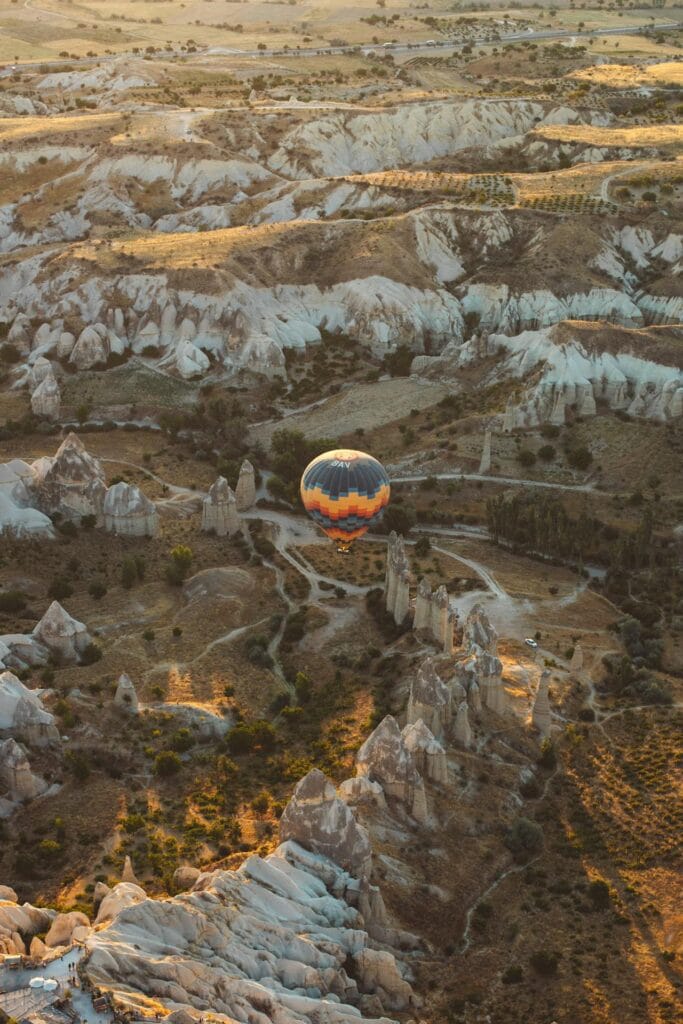 Multiple colorful hot air balloons floating over the unique fairy chimney rock formations in Cappadocia at sunrise.