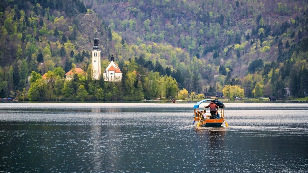 A traditional wooden boat (pletna) on Lake Bled with the iconic church on the island in the background.