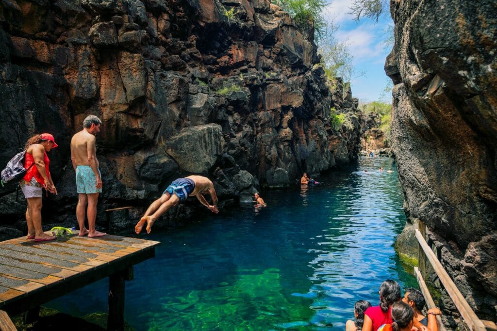 Travelers swimming in the crystal-clear coastal marine waters of the Galapagos Islands, Ecuador.