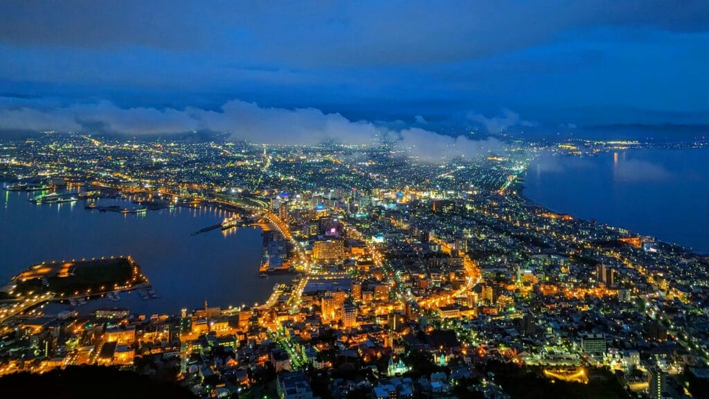 High-angle illuminated cityscape and grid streets of Sapporo at night from an aerial perspective in Hokkaido, Japan.