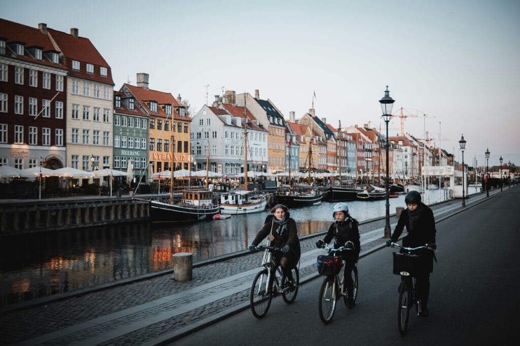A group of people riding bikes down a paved street, showcasing Danish cycling culture.