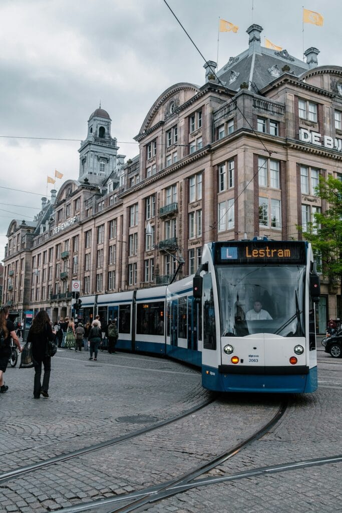 Blue and white Amsterdam tram on a city street, illustrating variable tram accessibility