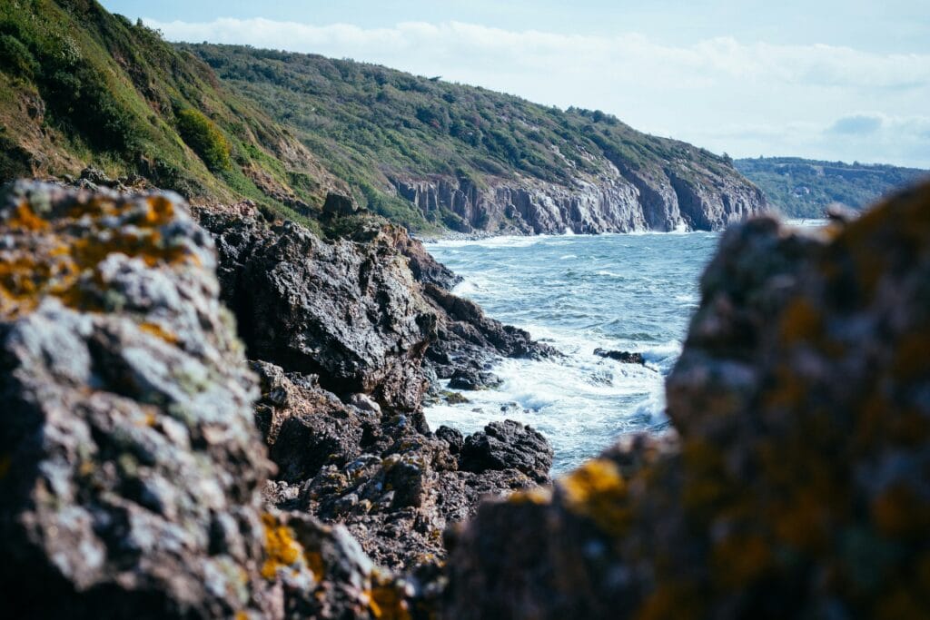 Rugged green trees covered mountains meeting the sea along the rocky Baltic coast of Bornholm, Denmark.