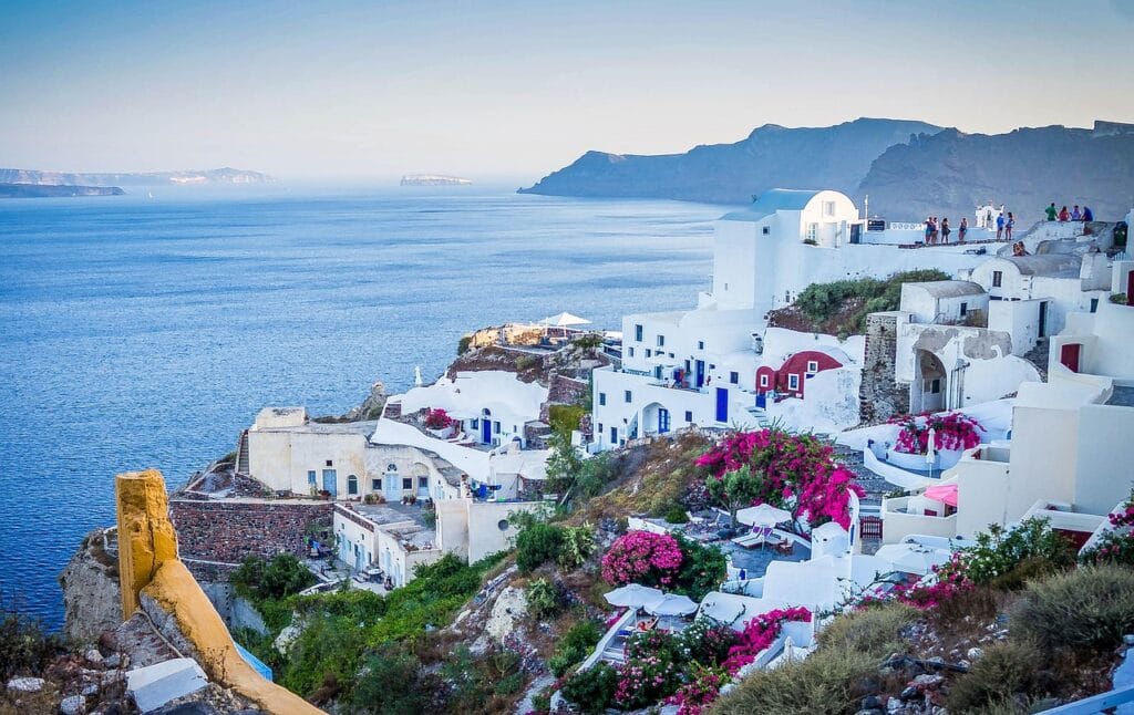 Classic white-washed houses and blue-domed buildings perched over the volcanic caldera cliffs in Santorini, Greece.