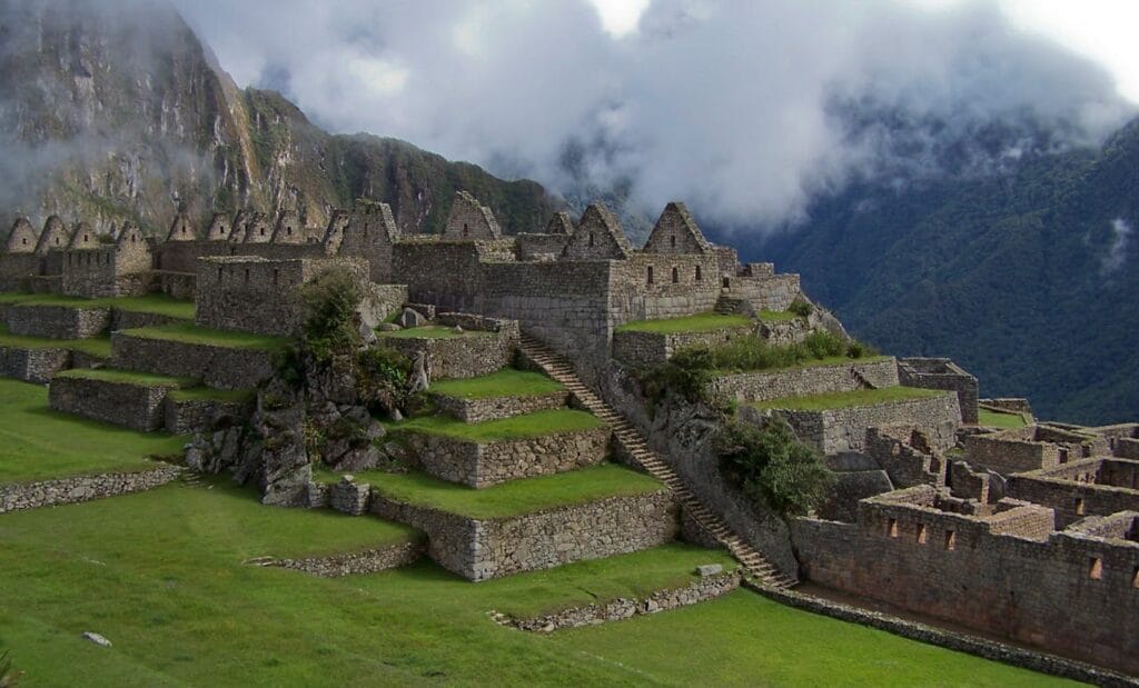 The ancient stone ruins of the Incan citadel Machu Picchu resting on a lush green mountain ridge under a clear blue sky in Peru