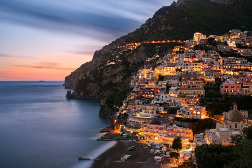 Colorful historic buildings terraced on a steep mountain slope in Salerno, Italy, next to the Tyrrhenian Sea.
