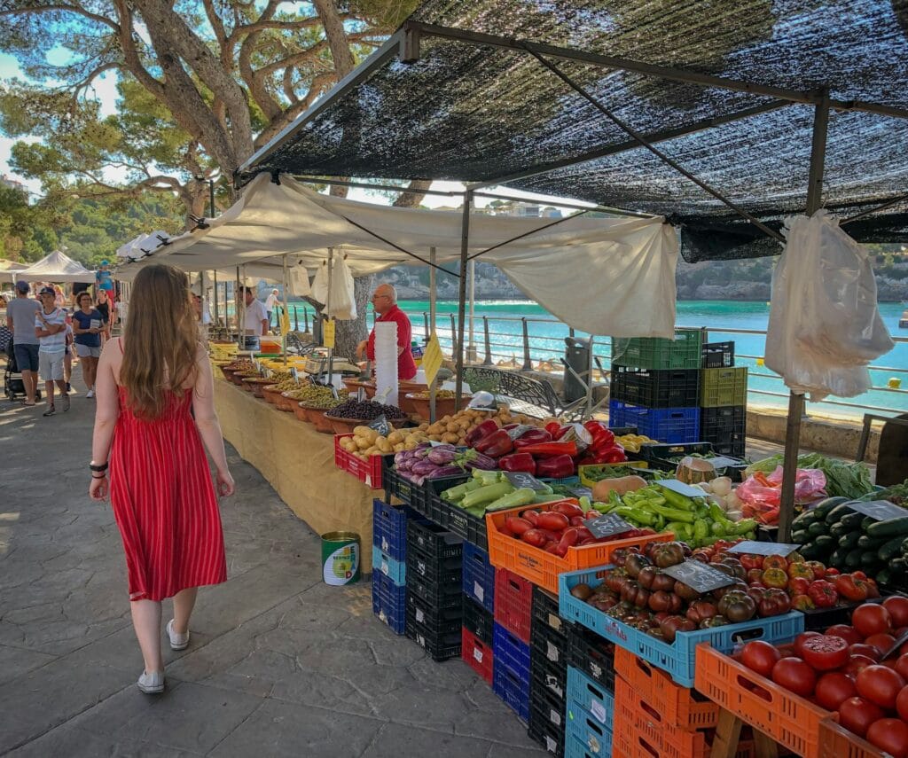 Local market stall in Porto, Portugal, displaying fresh vegetables, tomatoes, and produce with a shopper nearby
