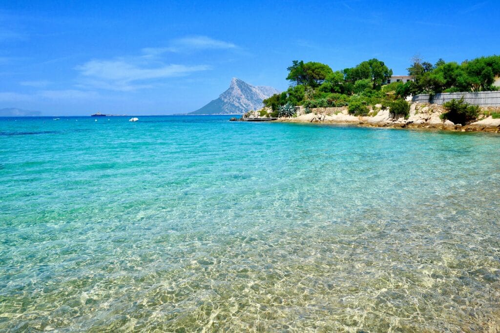 Crystal clear turquoise water at a beach in Sardinia, Italy, with rocky coastline