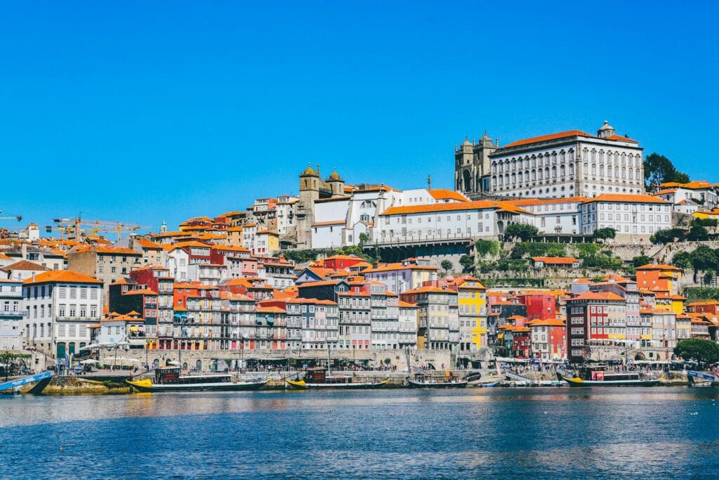 Scenic view of Porto, Portugal, along the Douro River with historic colorful buildings and traditional boats
