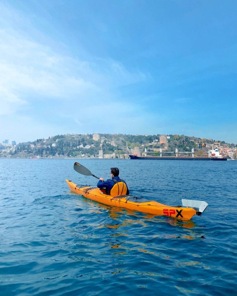 A person kayaking on the blue sea near the historic fortress and coastline of Dubrovnik, Croatia