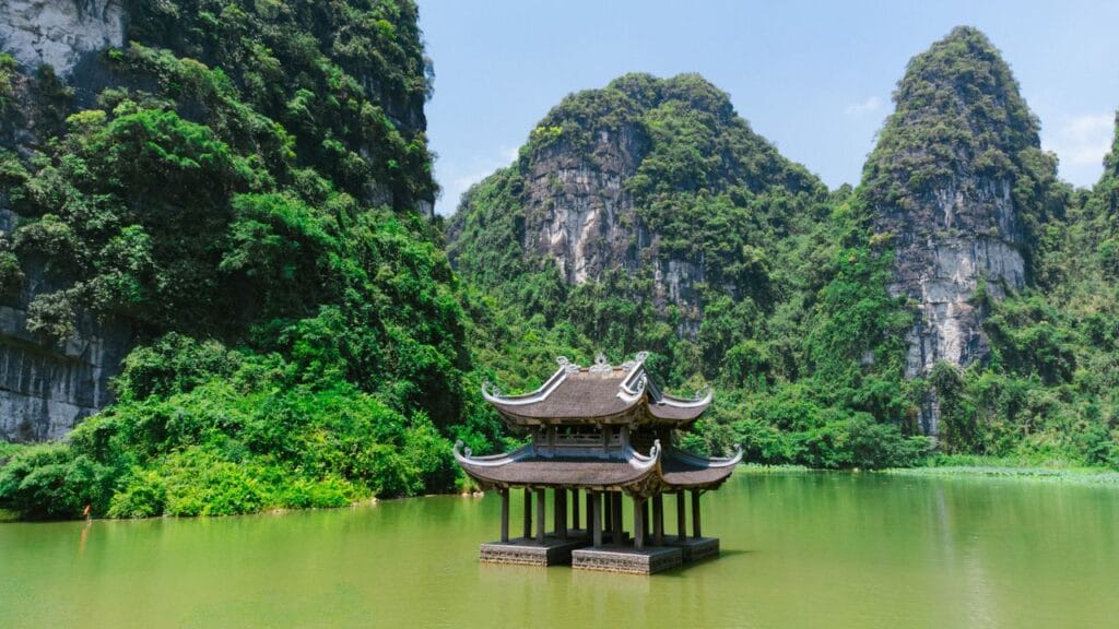 Tranquil pagoda and lush limestone karst landscape along a winding river in Ninh Binh, Vietnam