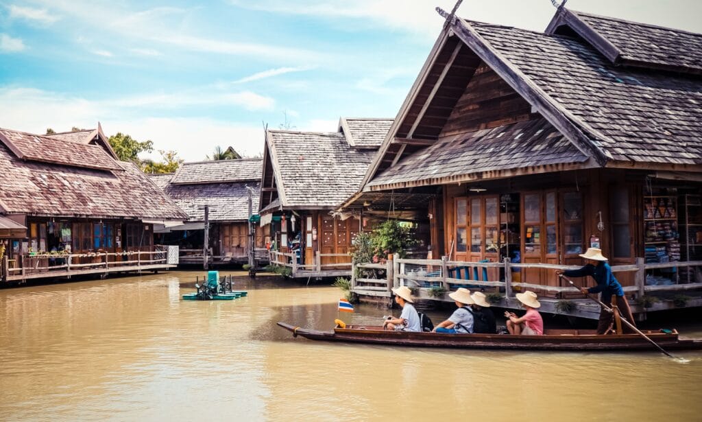Tourists riding a longtail boat through a traditional fishing village in Koh Yao Noi, Thailand.