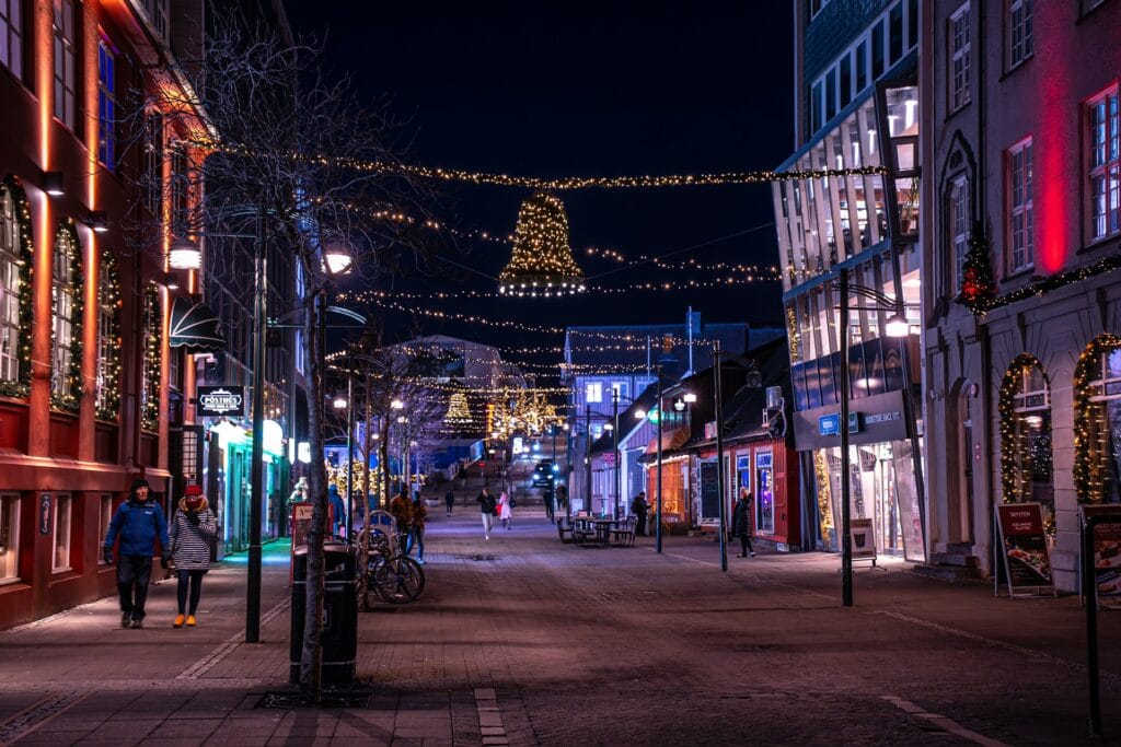 Festive hanging Christmas lights illuminating a quiet city street in Reykjavik, Iceland at night.
