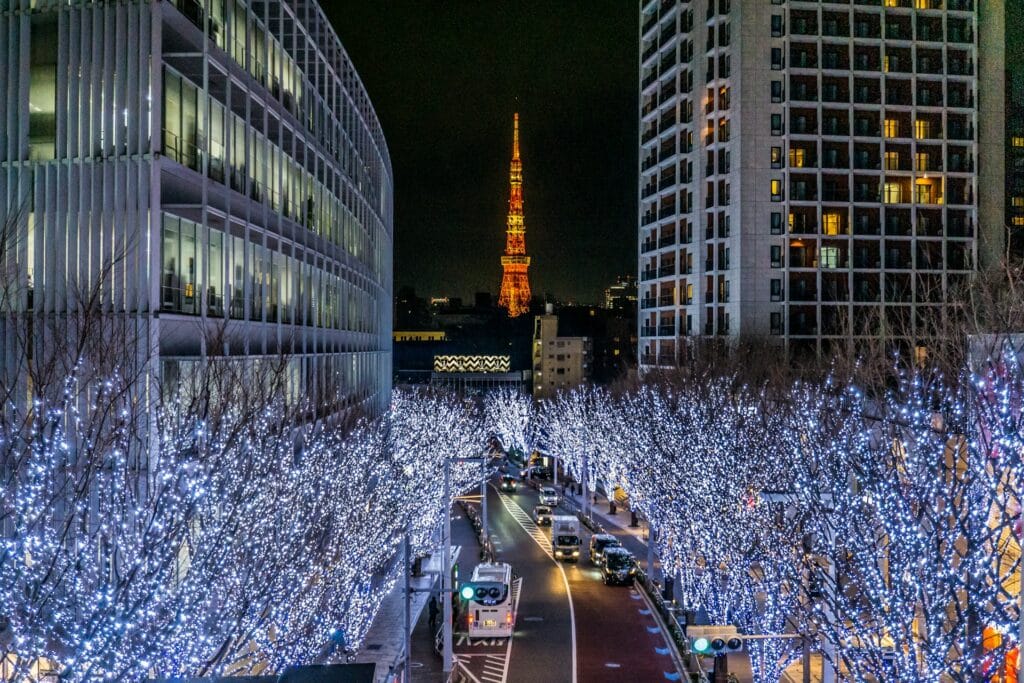 Blue and white illuminated trees framing a night view of Tokyo Tower in Tokyo, Japan
