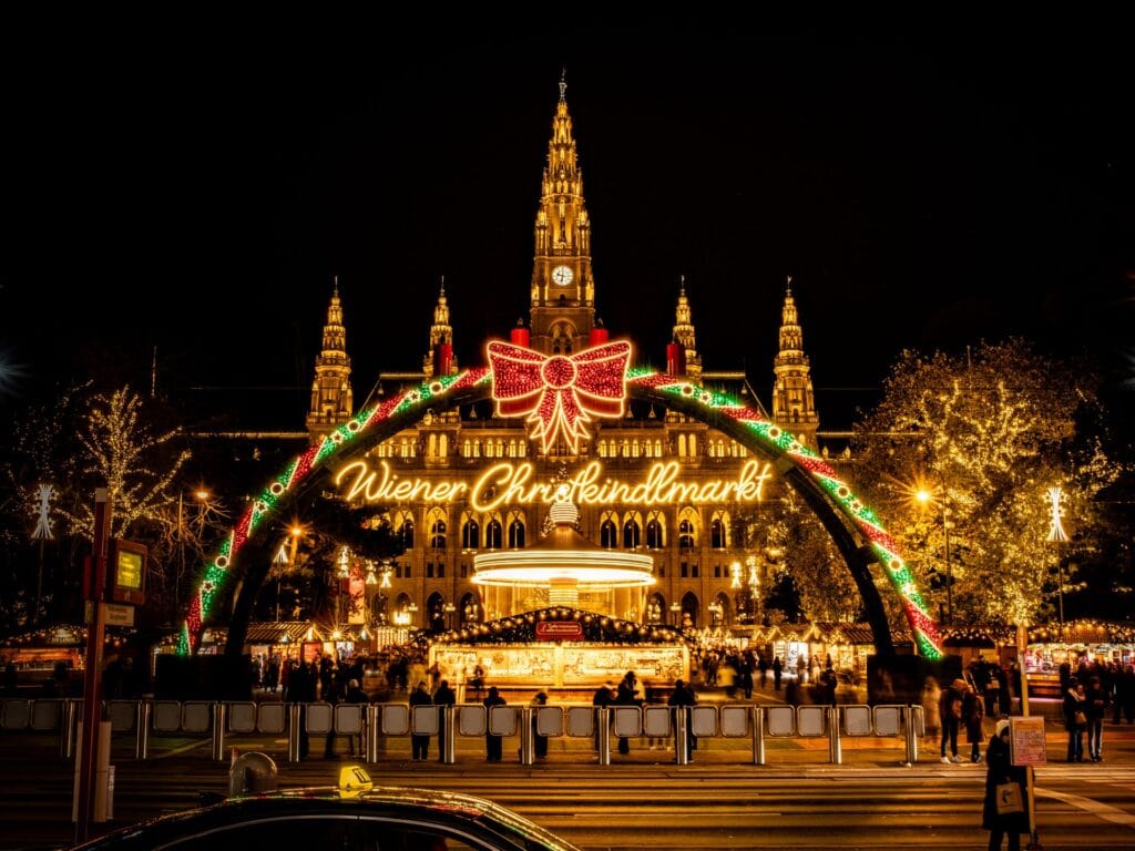 Festive Wiener Christkindlmarkt at night in front of the illuminated Rathausplatz in Vienna, Austria.