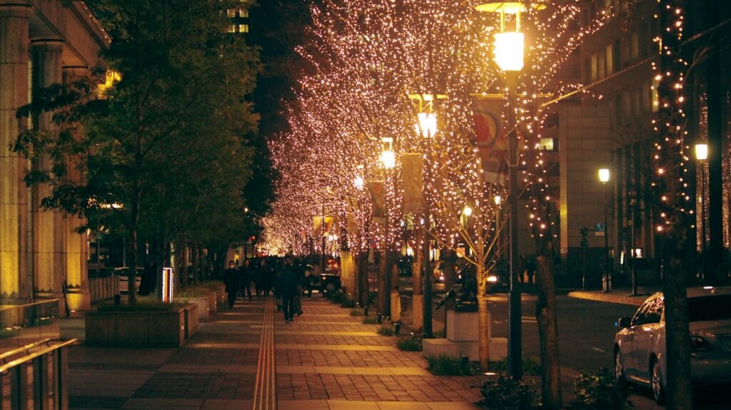 Trees along a city street glowing with golden winter illumination lights in Osaka, Japan.